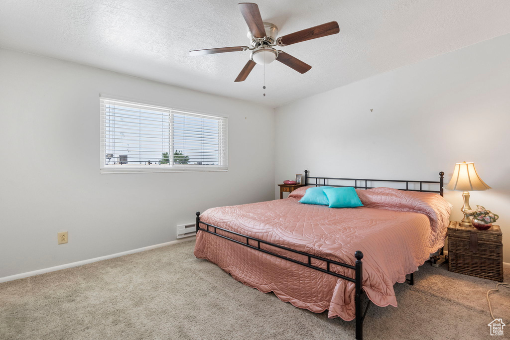 Carpeted bedroom with baseboard heating and ceiling fan