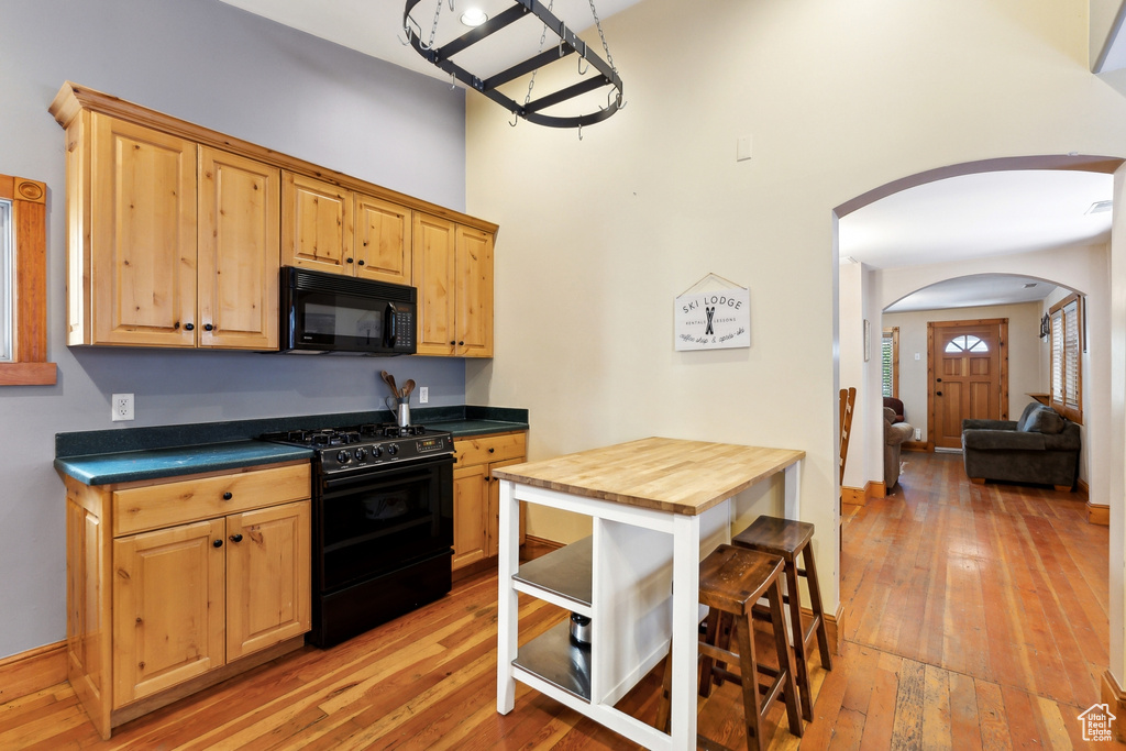 Kitchen featuring butcher block countertops, light wood-type flooring, and black appliances