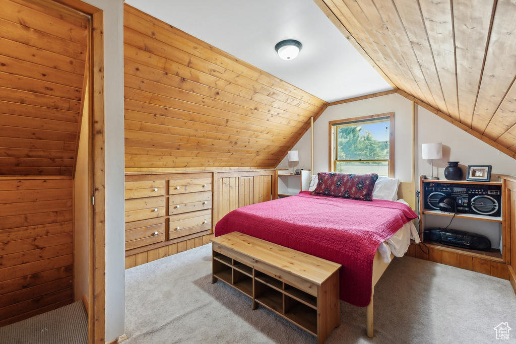 Carpeted bedroom with wooden ceiling, wooden walls, and lofted ceiling