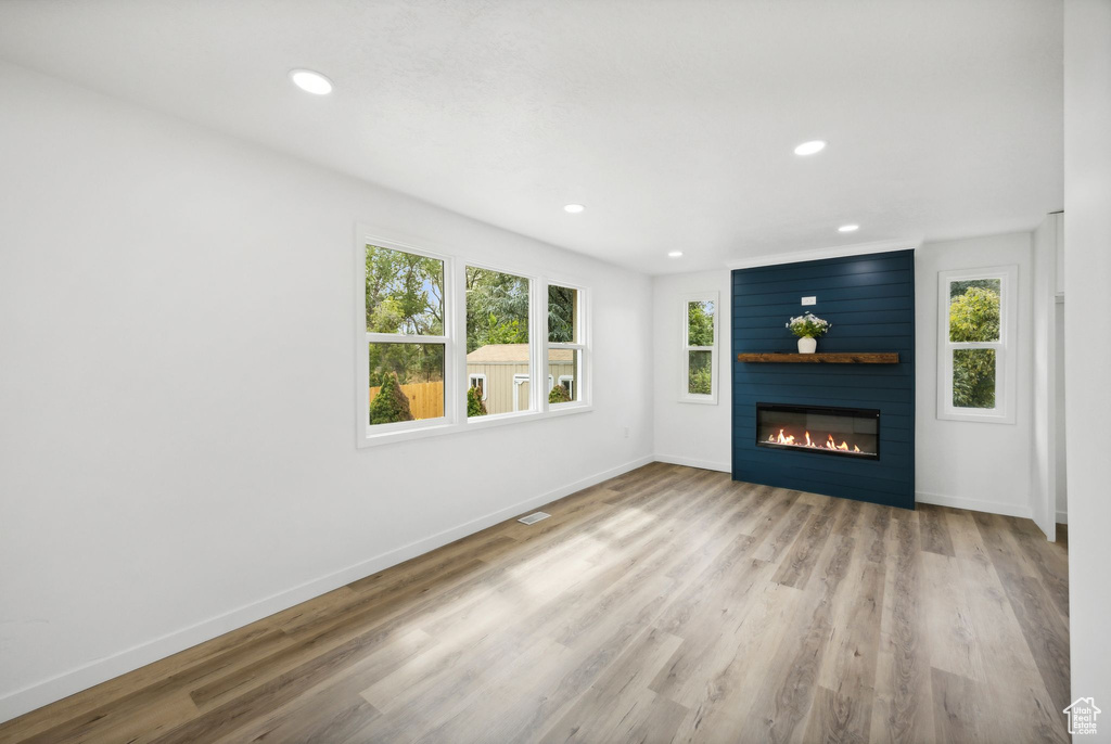 Unfurnished living room featuring a fireplace, light wood-type flooring, and a healthy amount of sunlight