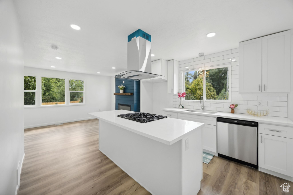 Kitchen featuring island exhaust hood, dishwasher, a wealth of natural light, and light wood-type flooring