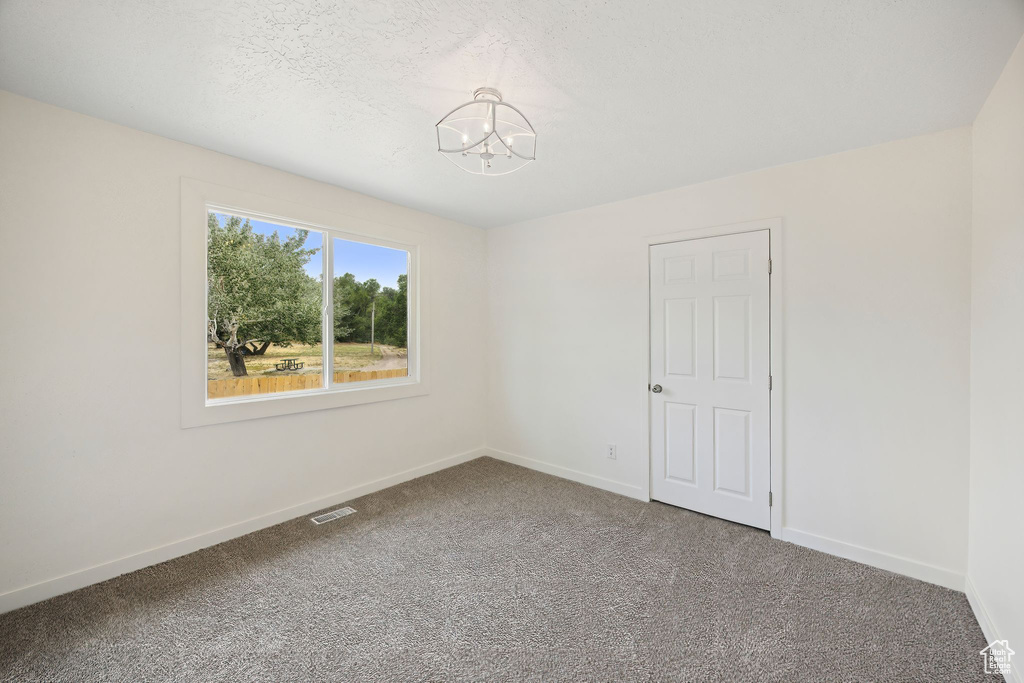 Carpeted spare room featuring a notable chandelier