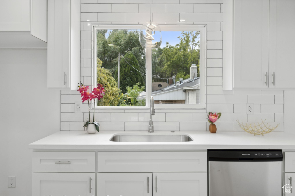 Kitchen featuring sink, dishwasher, decorative backsplash, and white cabinets