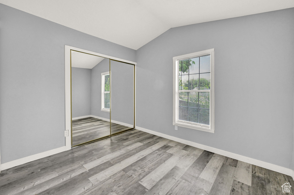 Unfurnished bedroom featuring a closet, hardwood / wood-style flooring, and vaulted ceiling