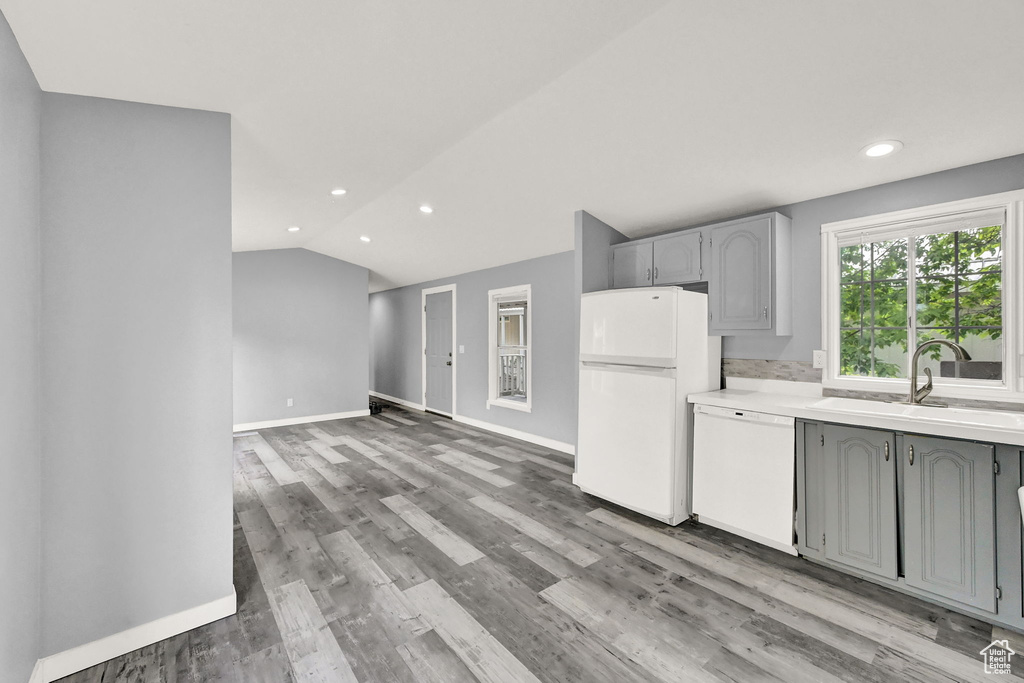 Kitchen with hardwood / wood-style flooring, white appliances, sink, lofted ceiling, and gray cabinetry