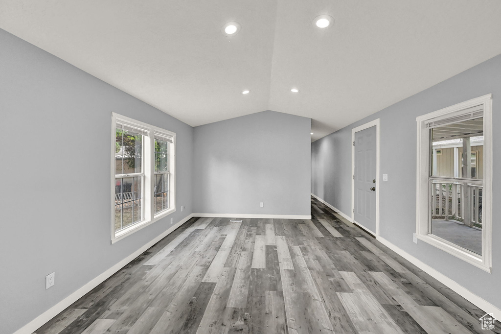 Unfurnished room with hardwood / wood-style flooring and lofted ceiling