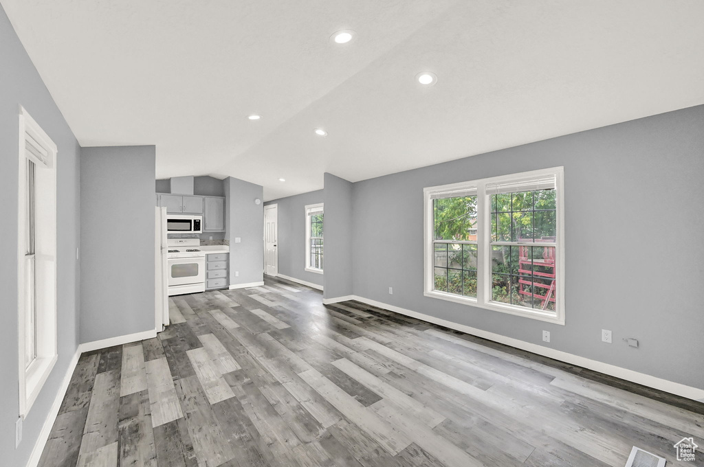 Unfurnished living room with wood-type flooring and vaulted ceiling