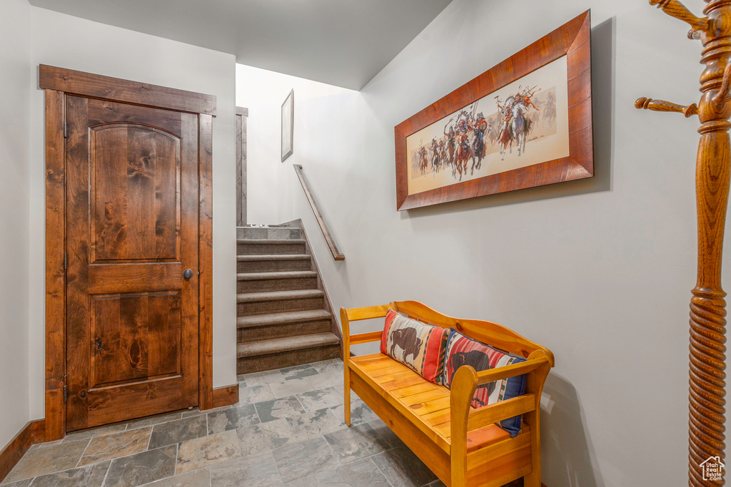 Foyer with stone finish flooring, baseboards, and stairs