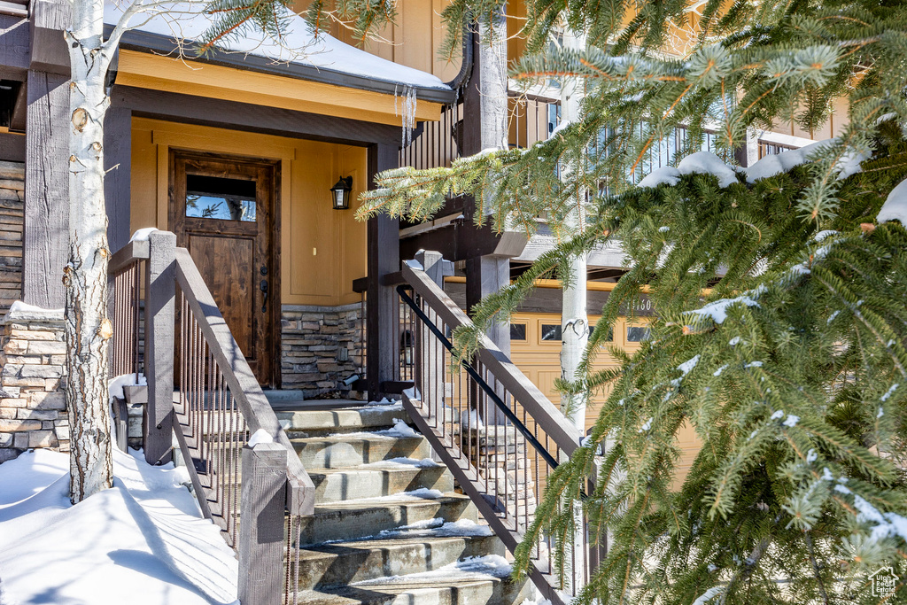 Snow covered property entrance featuring stone siding