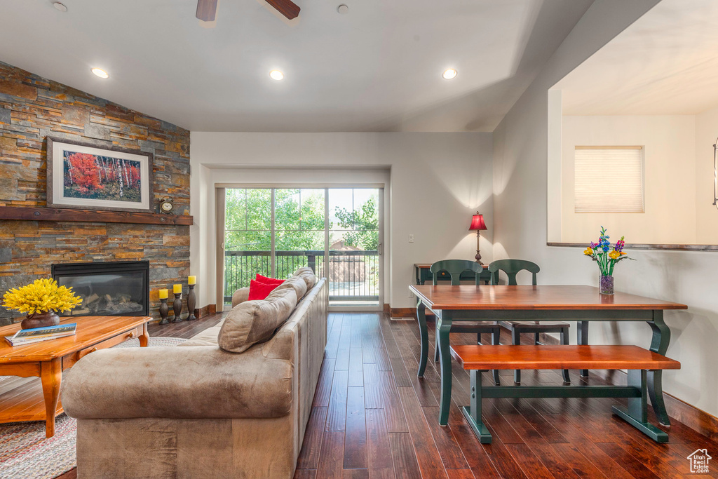 Living area featuring baseboards, a fireplace, ceiling fan, and dark wood-style flooring
