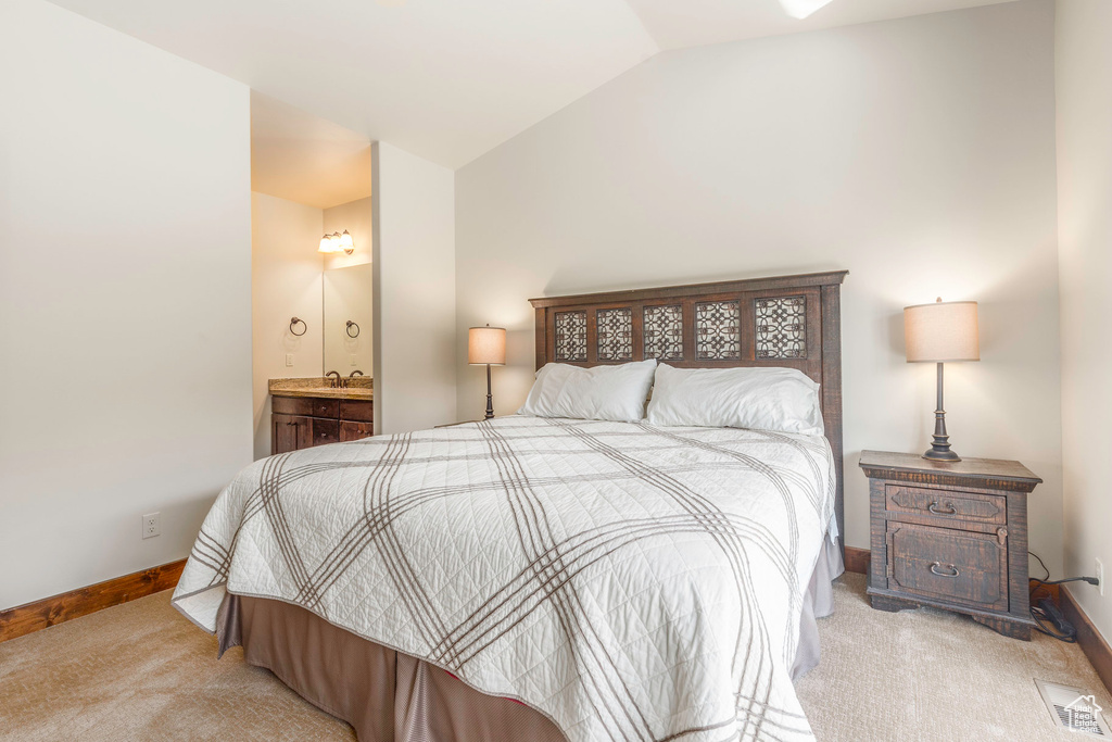 Carpeted bedroom with vaulted ceiling, a sink, connected bathroom, baseboards, and visible vents