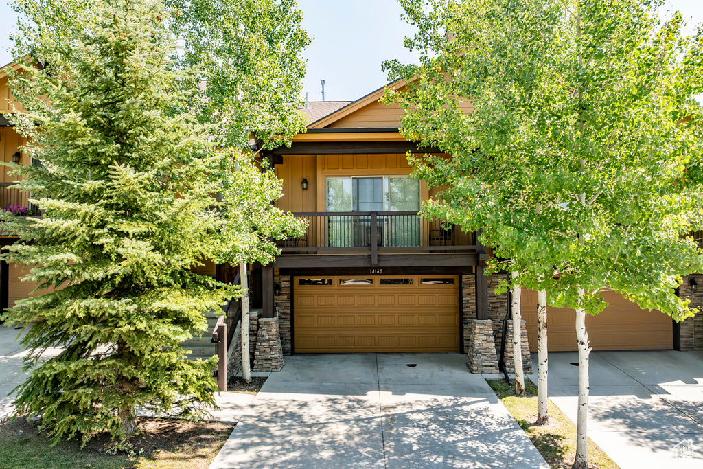 View of front facade featuring concrete driveway, an attached garage, and stone siding