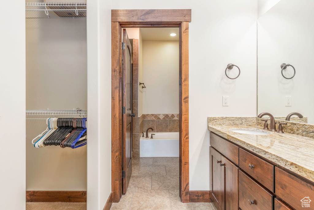 Bathroom featuring baseboards, a garden tub, and vanity