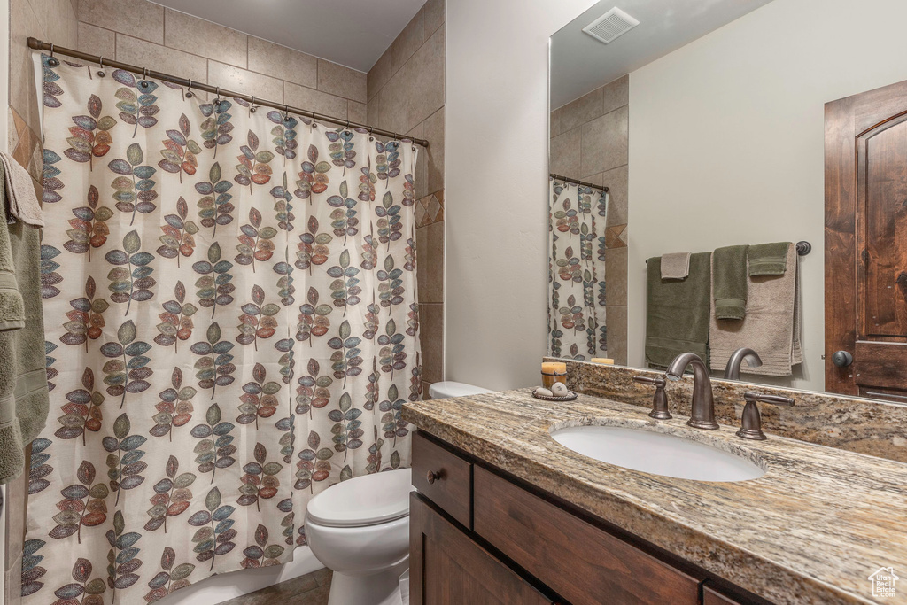Bathroom with toilet, a shower with curtain, vanity, and visible vents