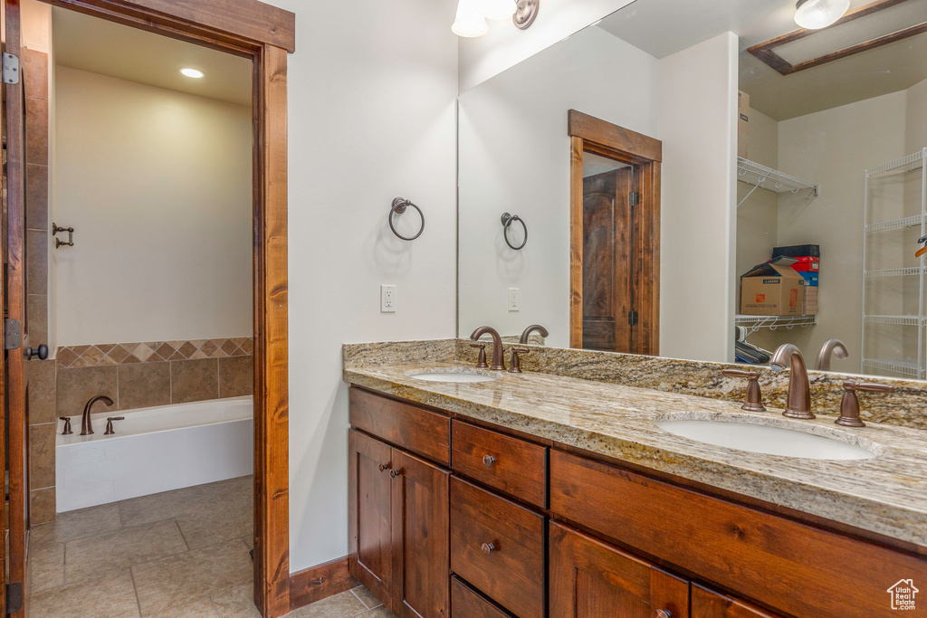 Full bath with tile patterned flooring, a sink, double vanity, and a bathtub