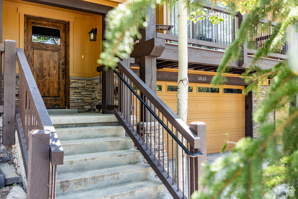 Doorway to property with stone siding and a garage