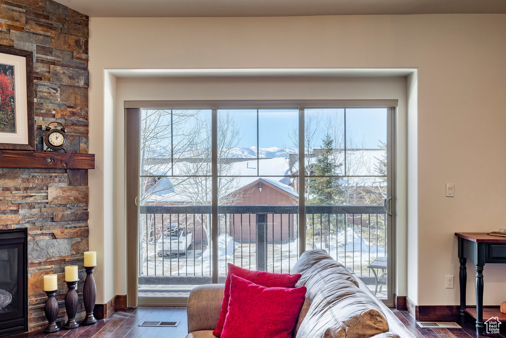 Living room featuring wood finished floors, baseboards, and a stone fireplace