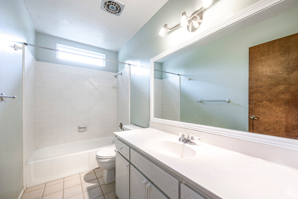 Full bathroom featuring vanity, tiled shower / bath combo, toilet, and tile patterned floors