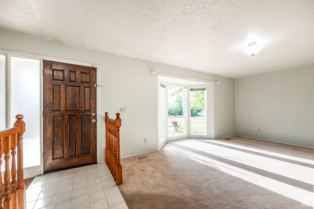 Carpeted entryway featuring a textured ceiling