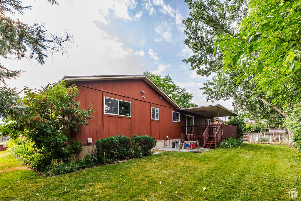 Back of property featuring a patio, a yard, and a wooden deck