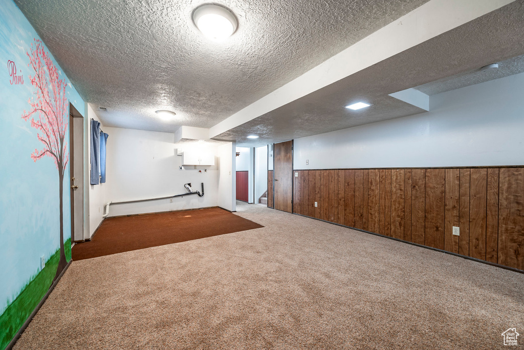 Basement featuring carpet, a baseboard radiator, and a textured ceiling