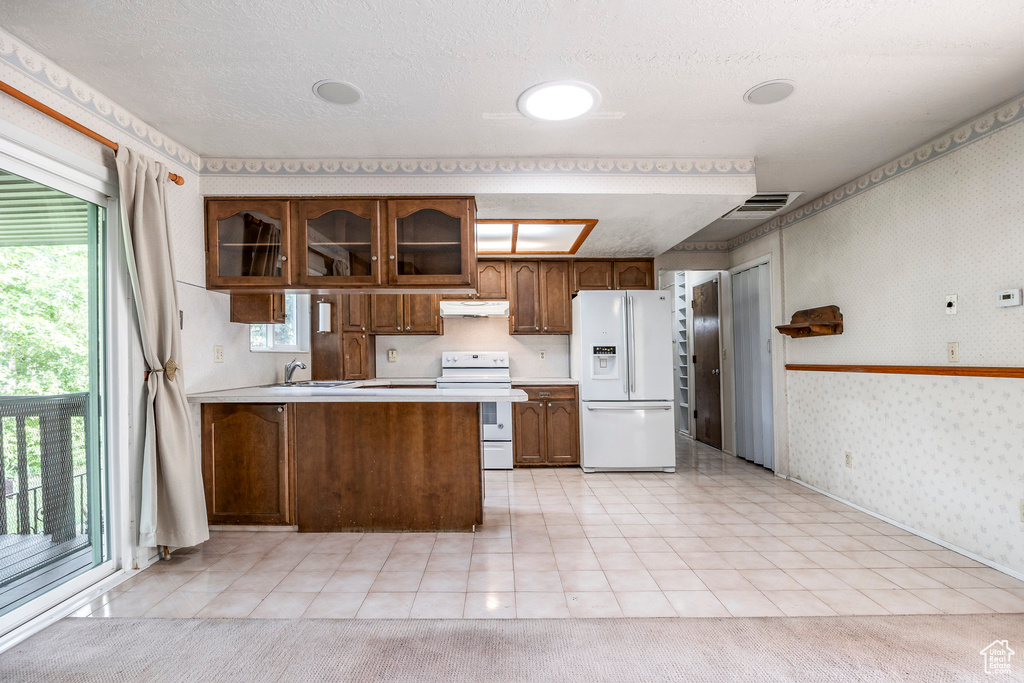 Kitchen featuring light colored carpet, white appliances, and kitchen peninsula