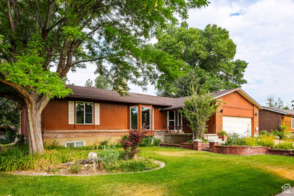 Single story home featuring a garage and a front yard