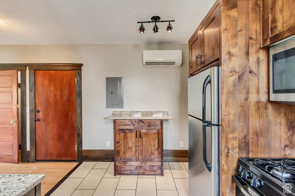 Kitchen with light wood-type flooring, electric panel, track lighting, appliances with stainless steel finishes, and a wall mounted air conditioner