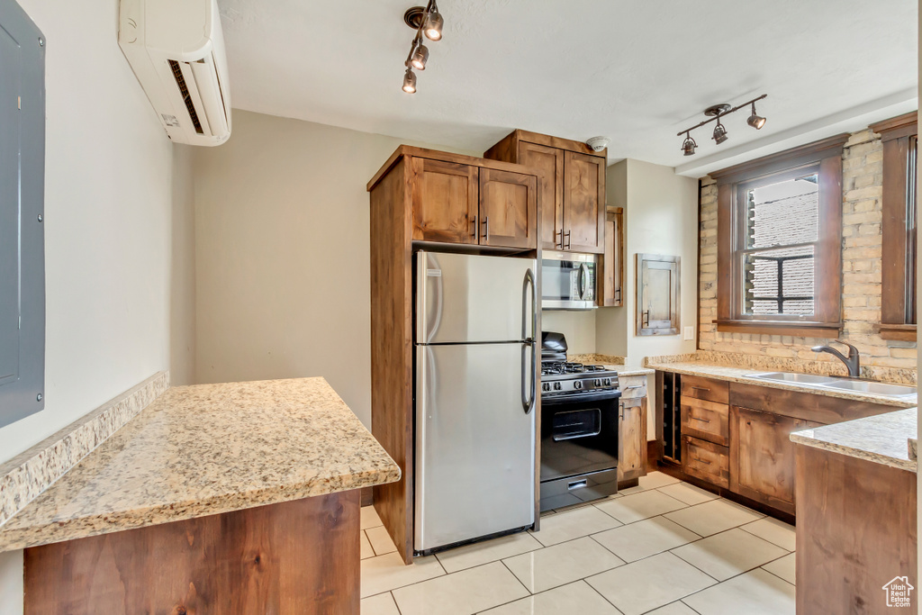 Kitchen with light tile patterned flooring, stainless steel appliances, a wall unit AC, sink, and track lighting