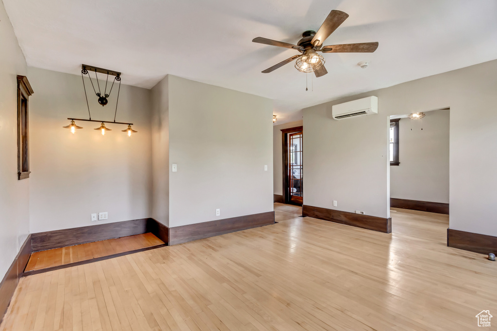 Unfurnished room with light hardwood / wood-style flooring, a wall mounted air conditioner, and ceiling fan