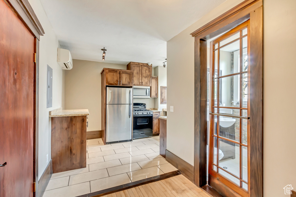 Kitchen featuring electric panel, stainless steel appliances, light hardwood / wood-style floors, and an AC wall unit