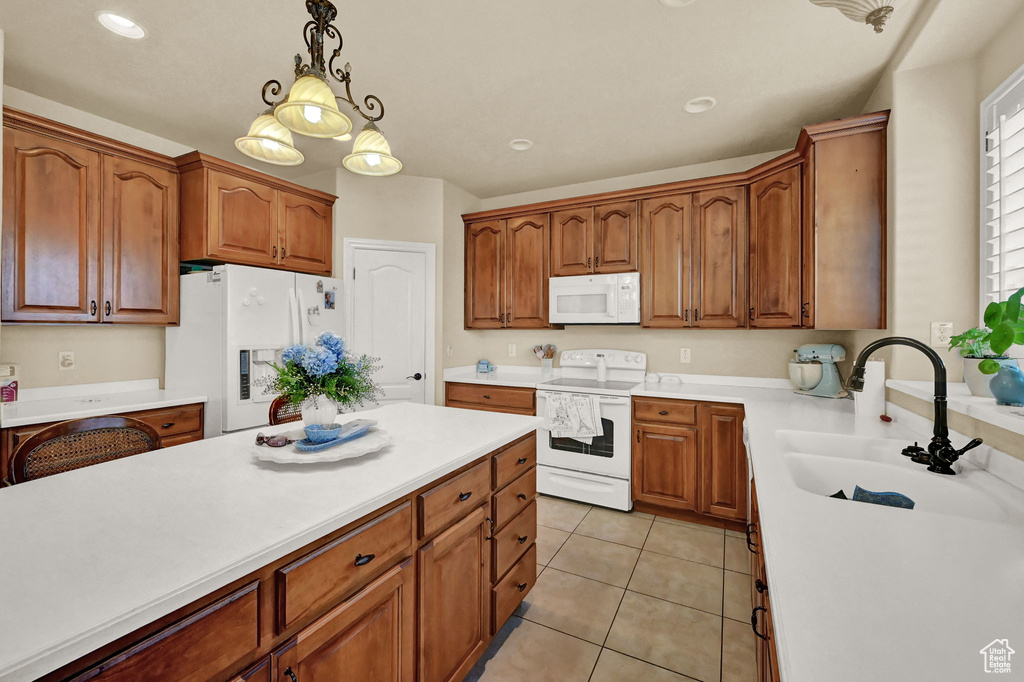 Kitchen featuring sink, pendant lighting, white appliances, and light tile patterned floors