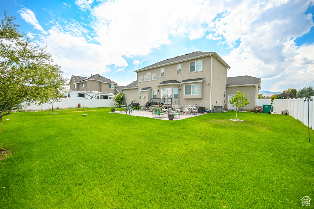 Rear view of house featuring cooling unit, a lawn, and a patio area