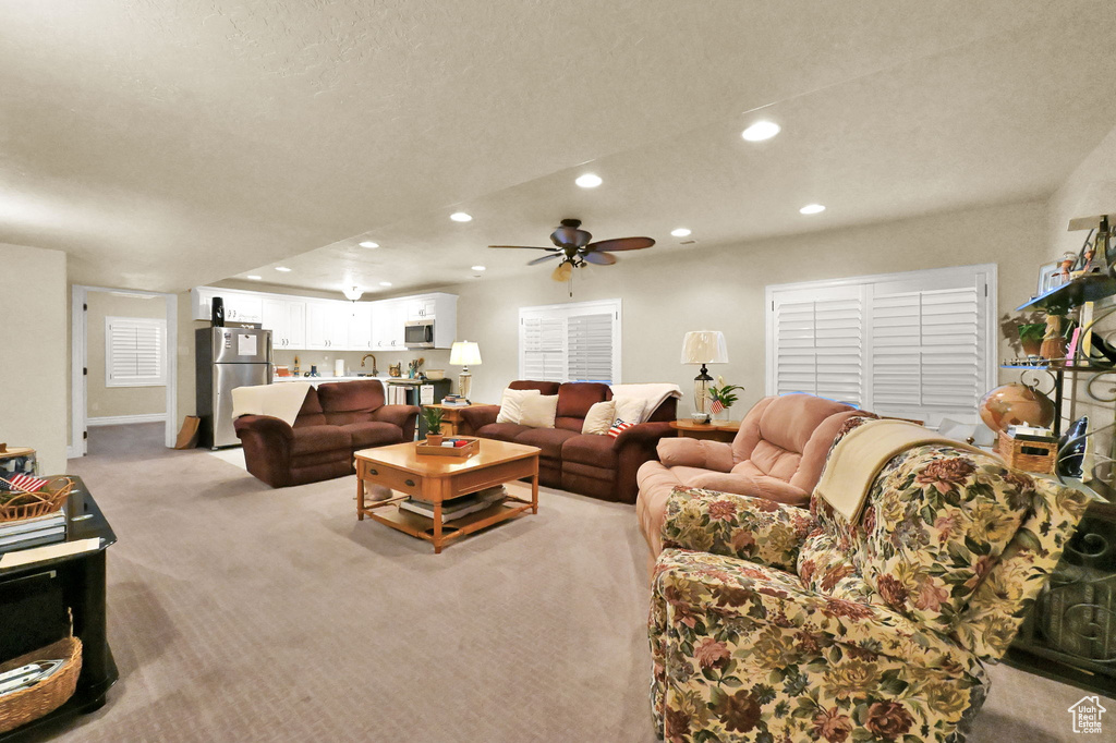 Living room featuring sink, light colored carpet, a textured ceiling, and ceiling fan