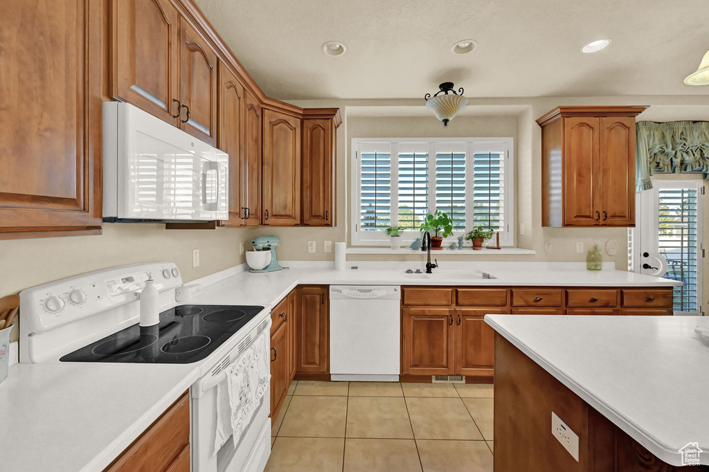 Kitchen featuring light tile patterned flooring, sink, white appliances, and a healthy amount of sunlight