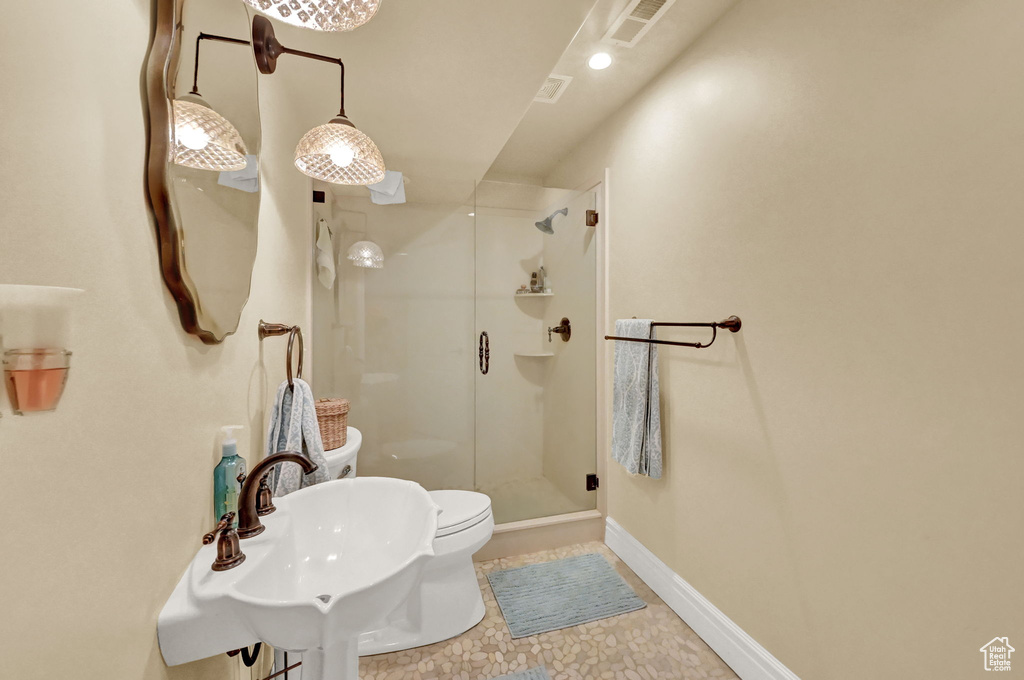 Bathroom featuring a shower with door, sink, tile patterned flooring, and toilet