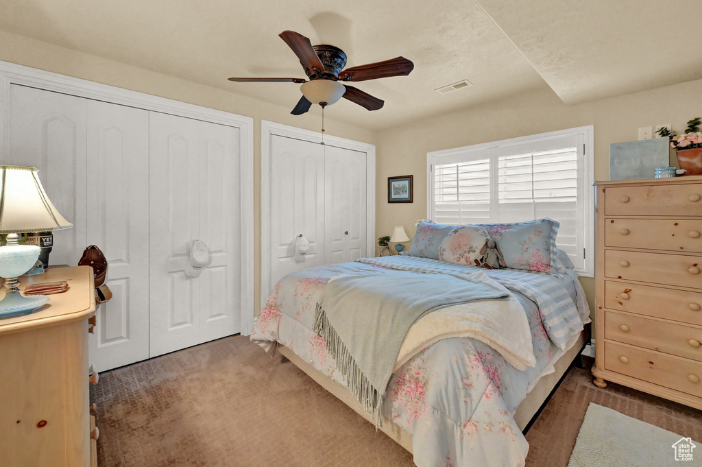 Bedroom featuring two closets, dark hardwood / wood-style flooring, and ceiling fan