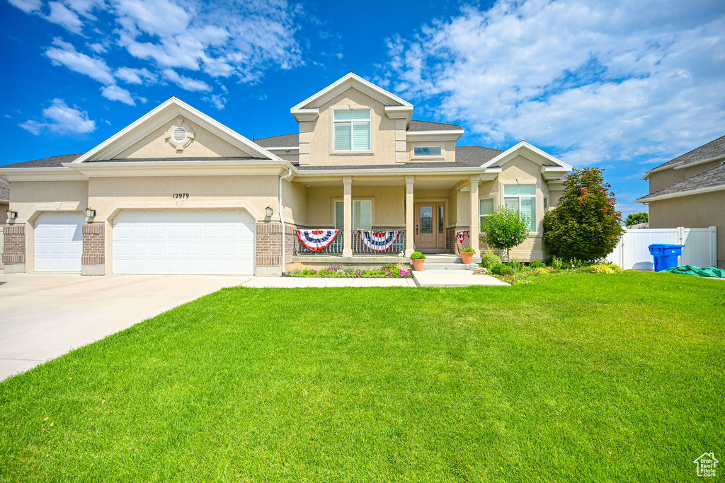 View of front facade with covered porch, a garage, and a front yard