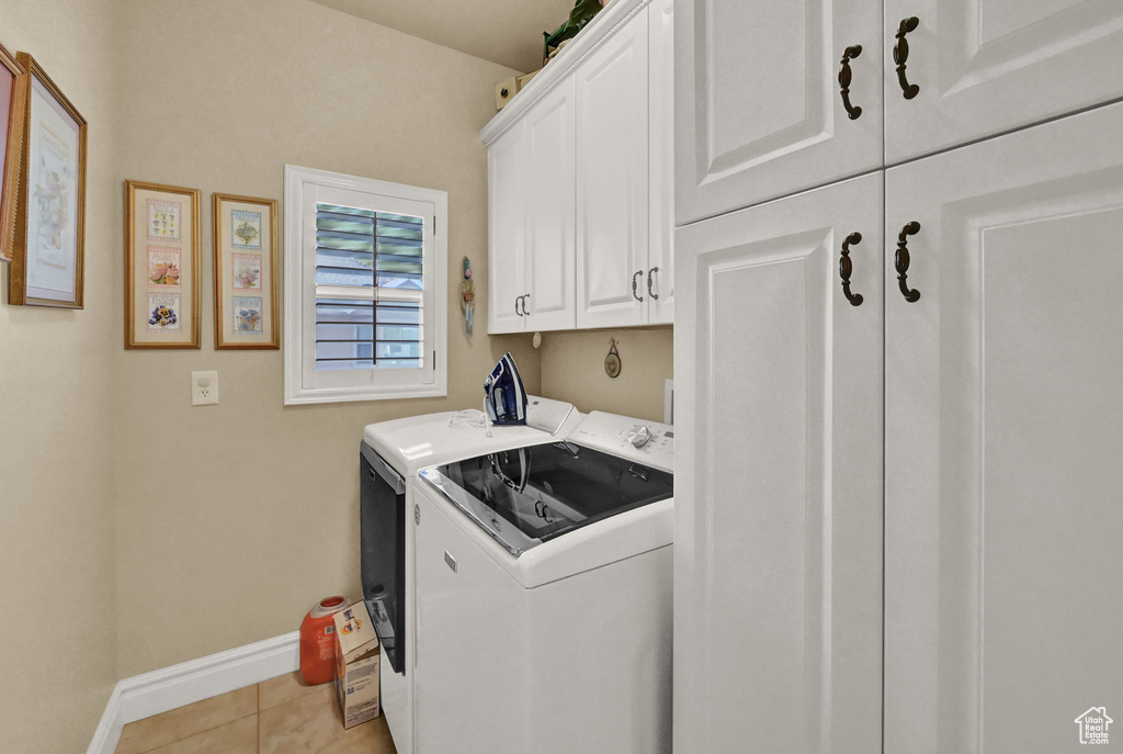 Clothes washing area with separate washer and dryer, cabinets, and light tile patterned floors