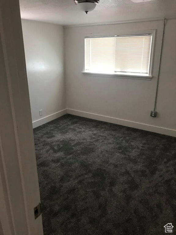 Unfurnished room featuring dark colored carpet