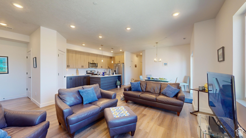 Living room with a chandelier and light hardwood / wood-style flooring