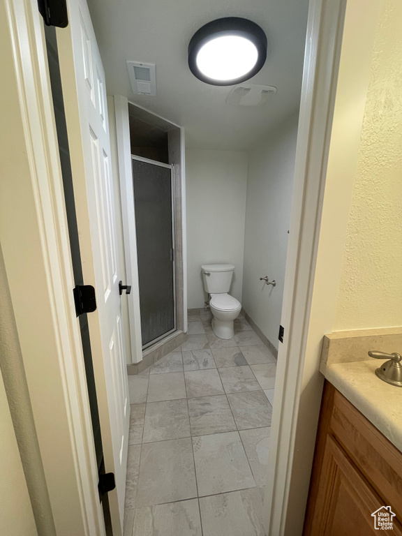 Bathroom featuring tile patterned floors, toilet, vanity, and an enclosed shower