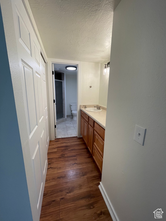 Bathroom with hardwood / wood-style flooring, toilet, vanity, and a textured ceiling