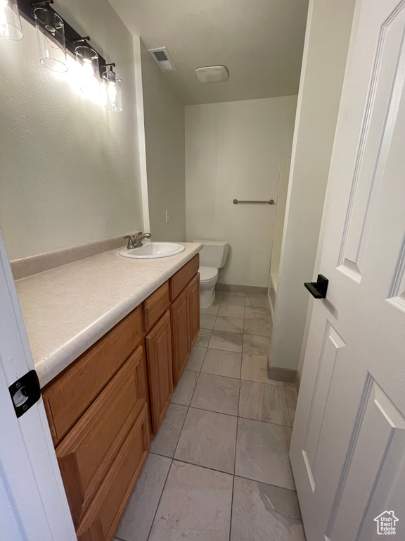 Bathroom with vanity, toilet, and tile patterned flooring