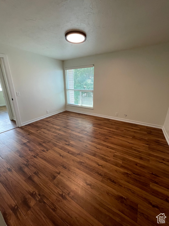 Spare room featuring dark wood-type flooring