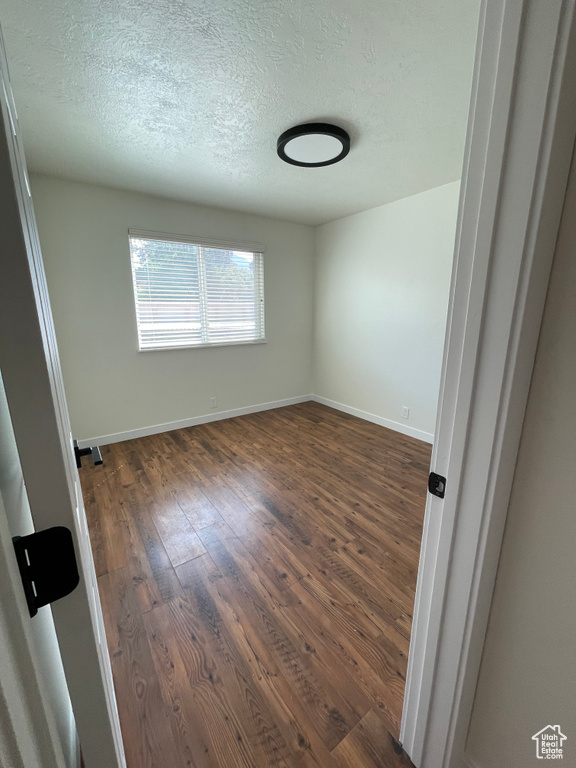 Unfurnished room featuring dark hardwood / wood-style floors and a textured ceiling