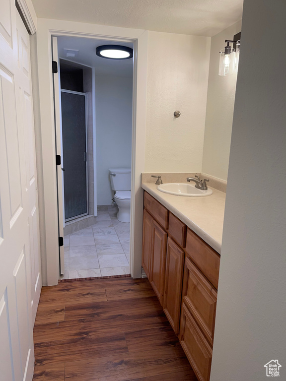 Bathroom featuring wood-type flooring, toilet, vanity, and an enclosed shower