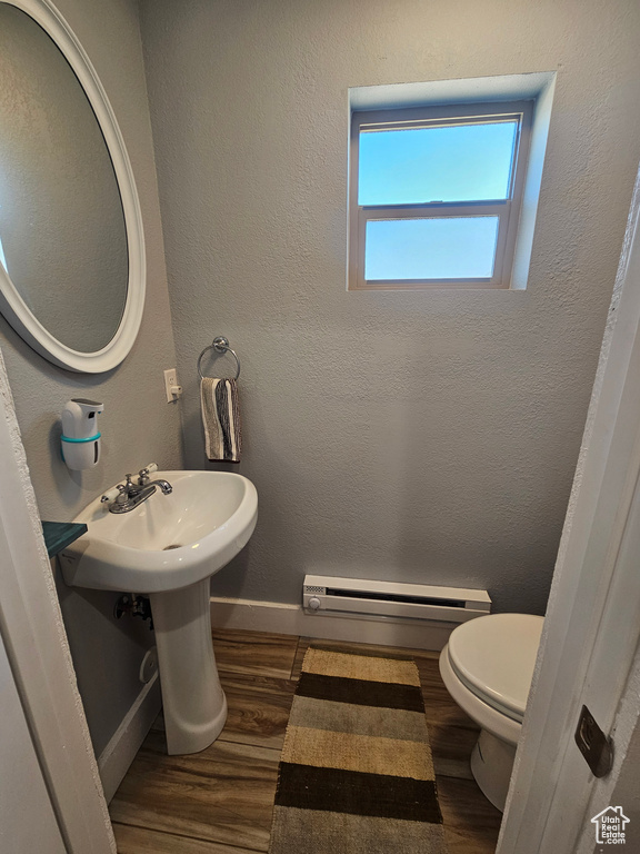 Bathroom with toilet, a baseboard heating unit, and hardwood / wood-style flooring