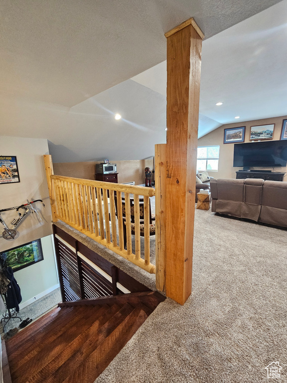 Stairs with carpet floors, a textured ceiling, and vaulted ceiling