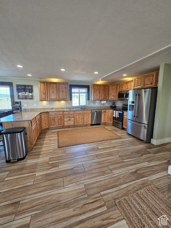 Kitchen featuring stainless steel appliances, light stone countertops, sink, and a textured ceiling